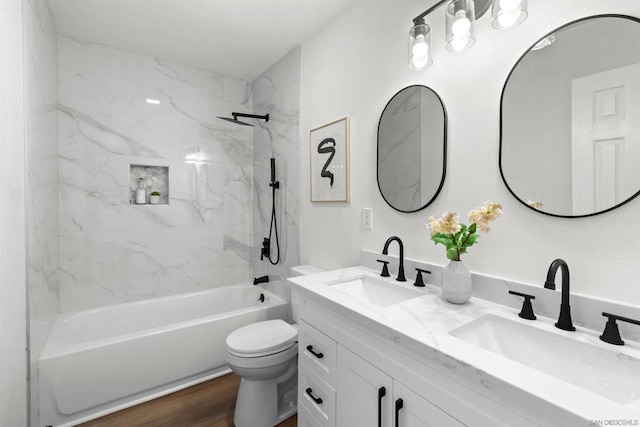 full bathroom with tiled shower / bath combo, wood-type flooring, toilet, and vanity