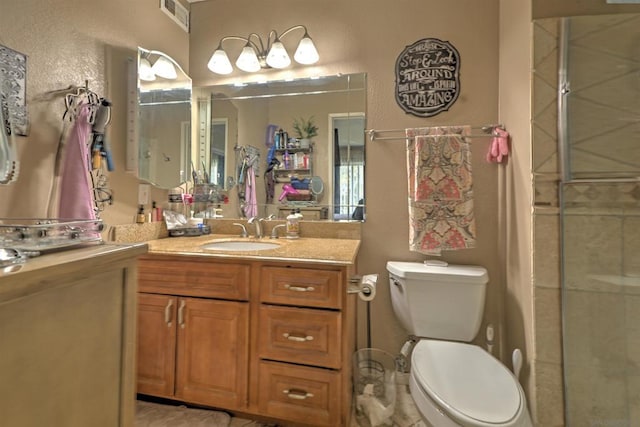 bathroom featuring a shower with door, toilet, and vanity