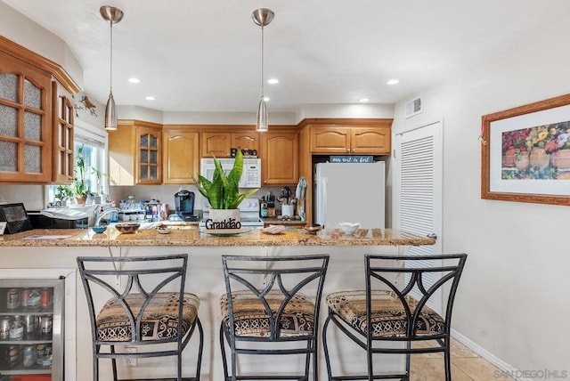 kitchen featuring white appliances, a breakfast bar area, wine cooler, and hanging light fixtures