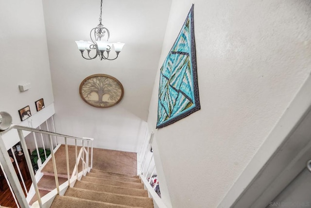 stairs featuring a chandelier