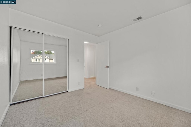 unfurnished bedroom with a closet and light carpet