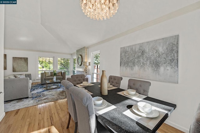 dining space featuring a notable chandelier, hardwood / wood-style floors, ornamental molding, and lofted ceiling