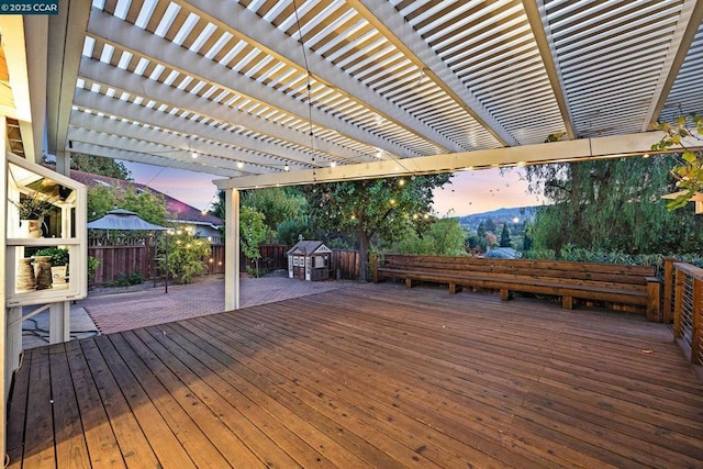 deck at dusk featuring a patio and a pergola