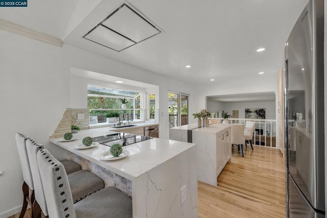 kitchen with a center island, appliances with stainless steel finishes, light wood-type flooring, sink, and kitchen peninsula