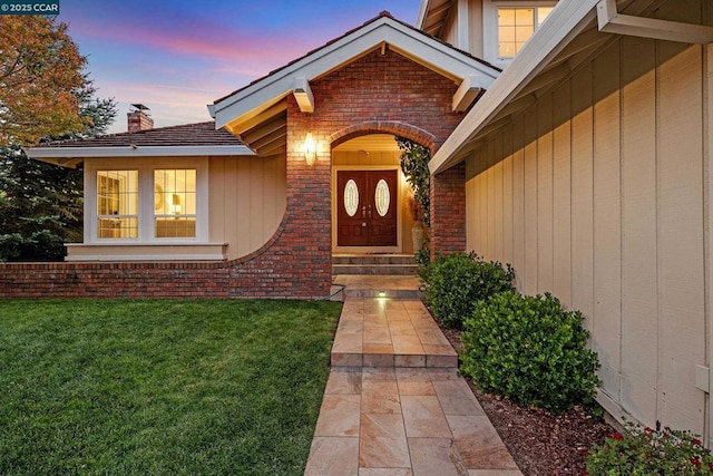 exterior entry at dusk featuring a yard