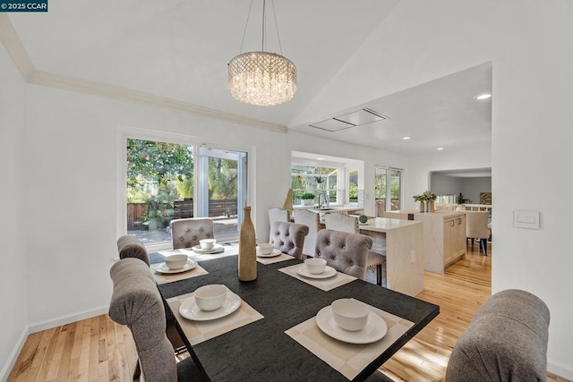 dining space with light hardwood / wood-style floors, lofted ceiling, and an inviting chandelier