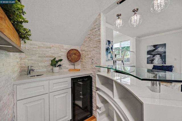 kitchen with white cabinets, beverage cooler, lofted ceiling, decorative light fixtures, and sink