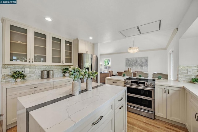 kitchen featuring a center island, hanging light fixtures, decorative backsplash, stainless steel appliances, and light stone counters