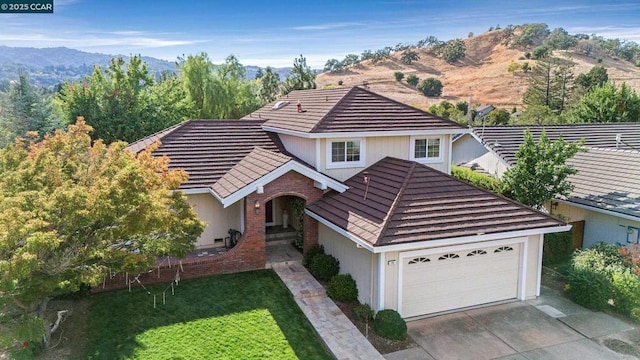 view of front of house featuring a garage, a front lawn, and a mountain view