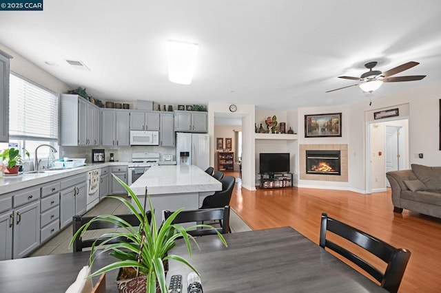 kitchen featuring sink, gray cabinets, white appliances, and light wood-type flooring