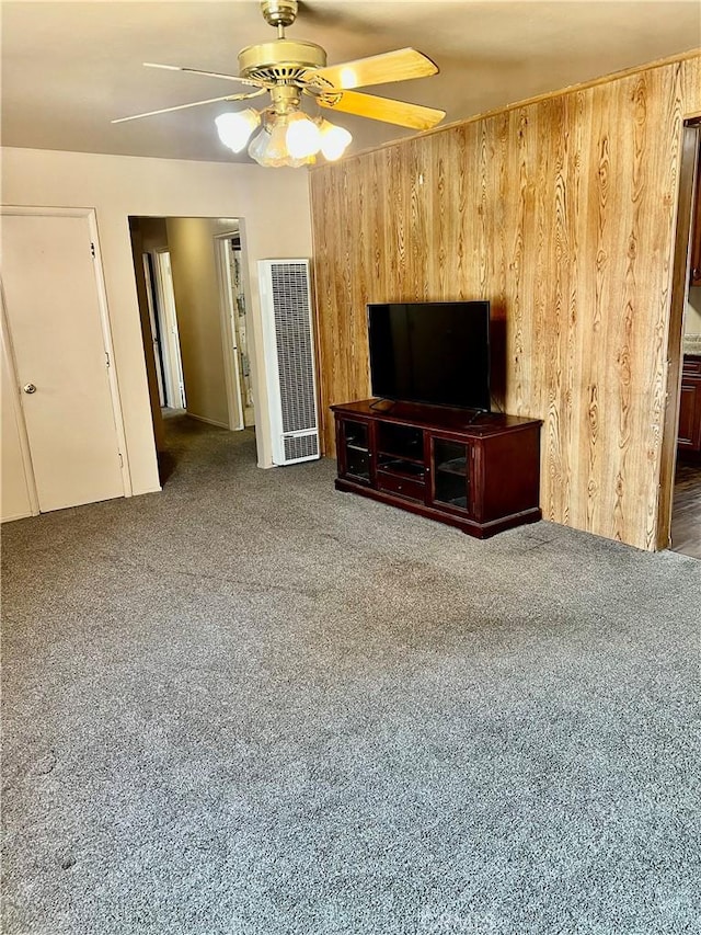 living room featuring ceiling fan, wood walls, and dark colored carpet