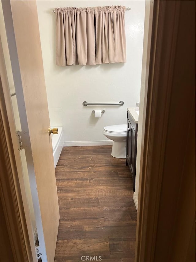 bathroom featuring hardwood / wood-style flooring, a bathtub, toilet, and vanity