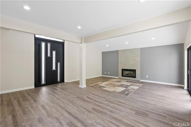 unfurnished living room with vaulted ceiling, wood-type flooring, and a fireplace