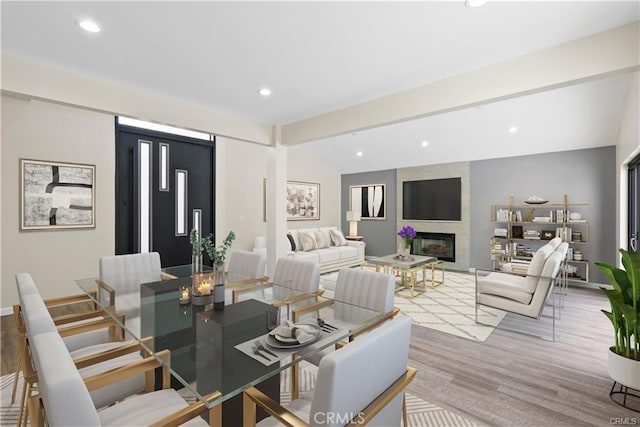 living room with lofted ceiling, wood-type flooring, and a large fireplace