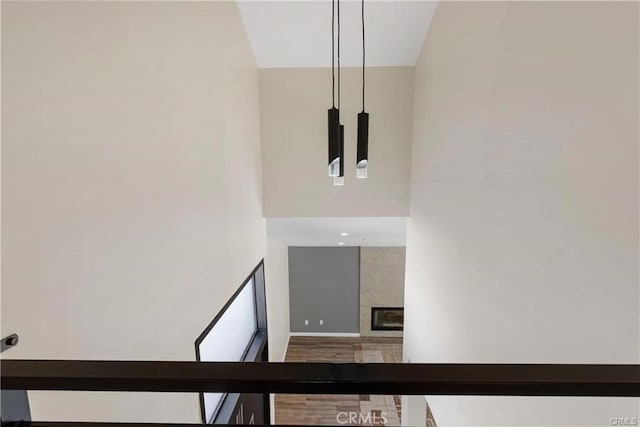 stairway featuring a large fireplace, hardwood / wood-style floors, and a towering ceiling