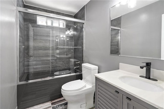 full bathroom with toilet, vanity, and bath / shower combo with glass door