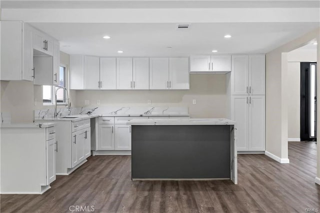 kitchen featuring dark wood-type flooring, sink, a kitchen island, and white cabinets