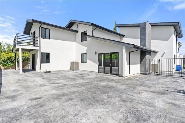 rear view of house with a patio, a balcony, and central AC