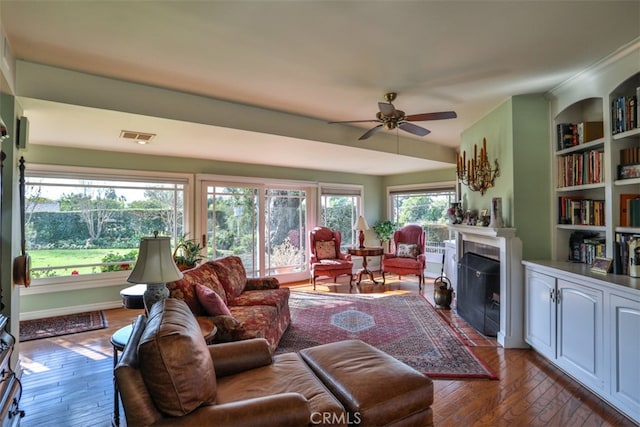 living room featuring built in features, ceiling fan, and hardwood / wood-style floors