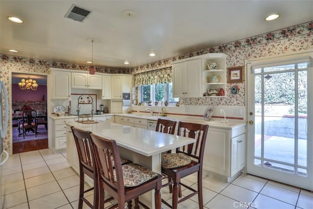 kitchen with sink, white cabinets, a center island, and light tile patterned flooring