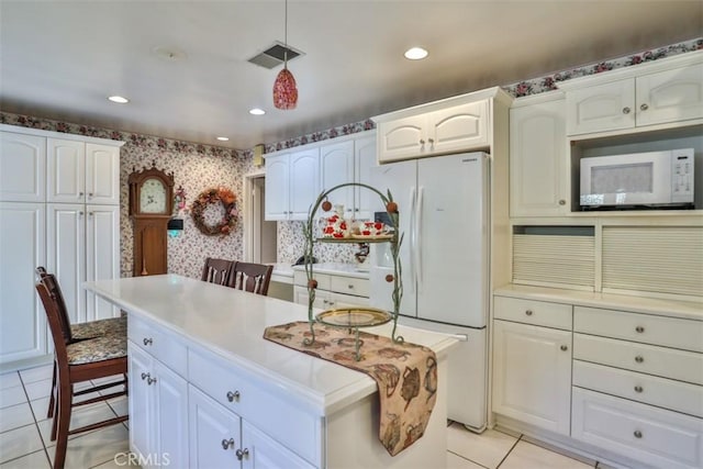 kitchen with white appliances, white cabinets, a center island, and light tile patterned flooring