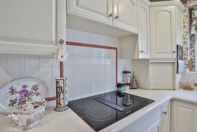 kitchen featuring black electric cooktop, white cabinets, and decorative backsplash