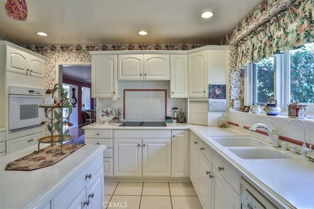 kitchen featuring sink, backsplash, white cabinets, light tile patterned flooring, and white appliances