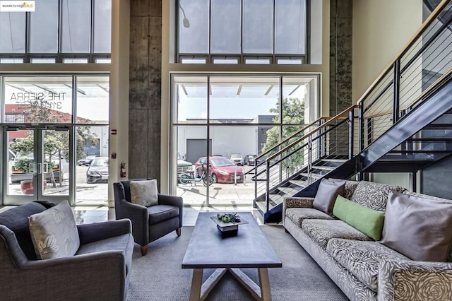 living room with a towering ceiling, french doors, and carpet flooring