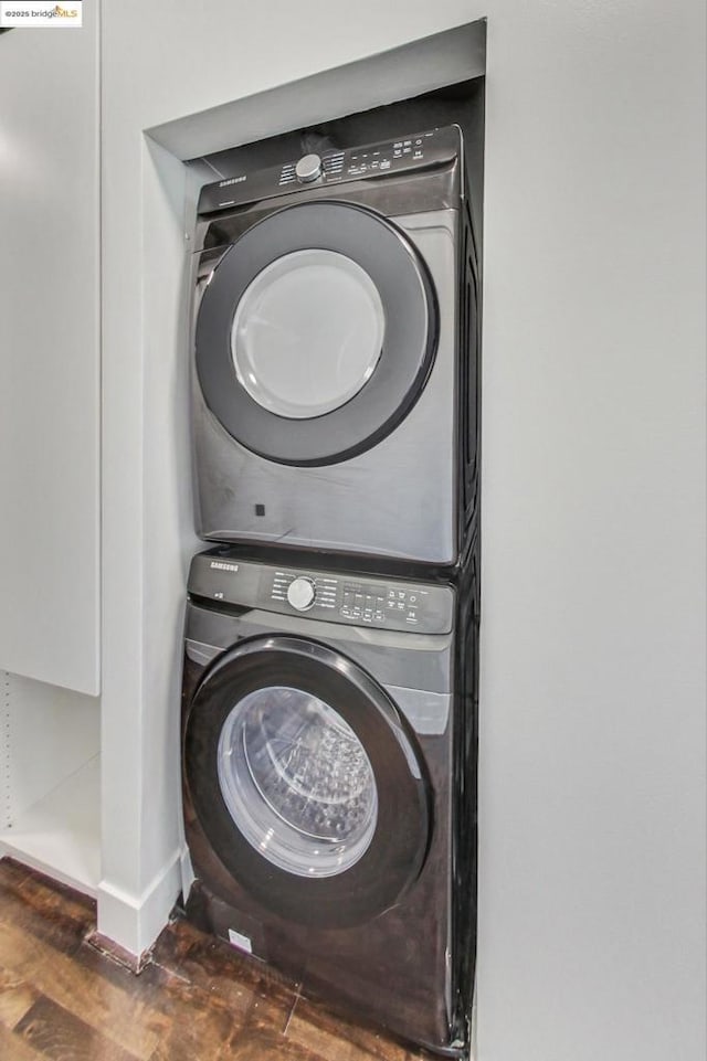 laundry room with stacked washer / dryer and dark wood-type flooring