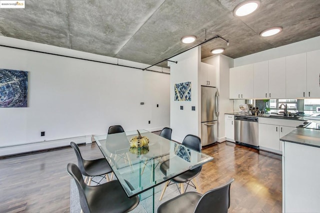 dining area with dark wood-type flooring, a baseboard heating unit, and sink