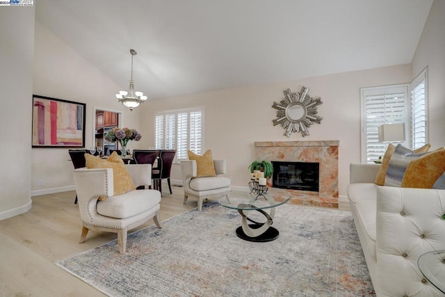 living room featuring vaulted ceiling, a chandelier, a high end fireplace, and light hardwood / wood-style floors