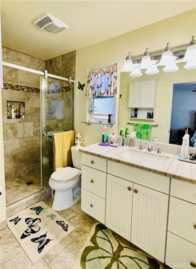 bathroom featuring a shower with door, toilet, and vanity