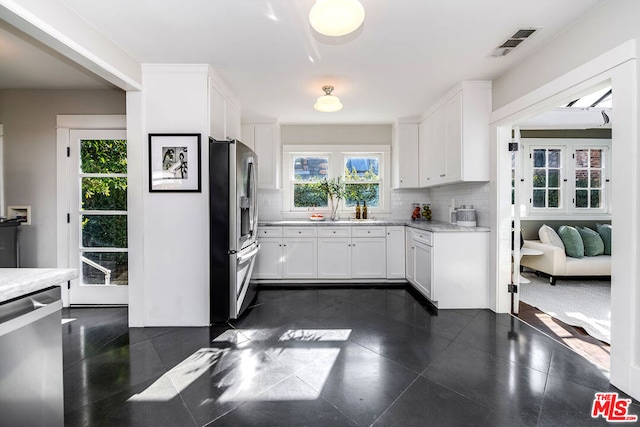 kitchen with appliances with stainless steel finishes, sink, white cabinets, light stone counters, and decorative backsplash