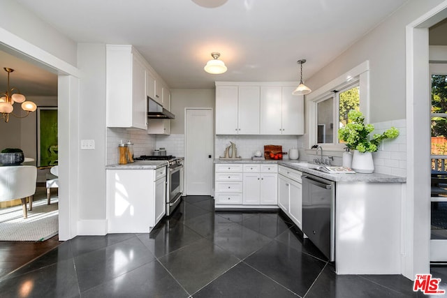 kitchen with pendant lighting, white cabinets, appliances with stainless steel finishes, tasteful backsplash, and sink