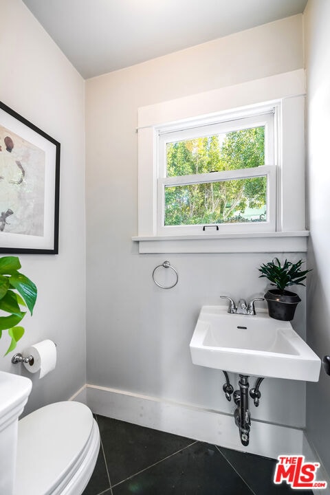 bathroom with toilet, tile patterned floors, and plenty of natural light