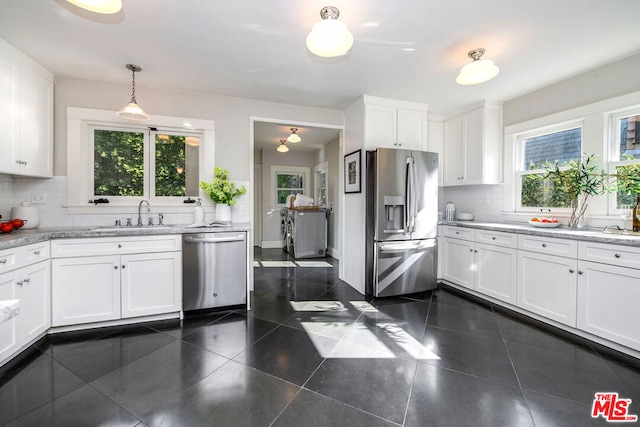 kitchen featuring white cabinets, appliances with stainless steel finishes, decorative light fixtures, decorative backsplash, and sink