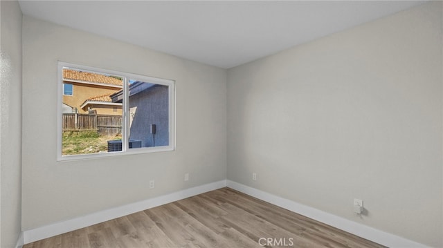 spare room with baseboards and wood finished floors