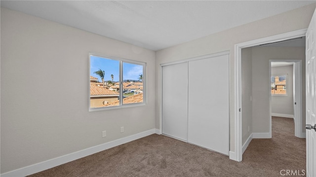 unfurnished bedroom with a closet, carpet, and baseboards