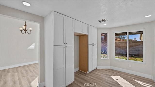 kitchen featuring white cabinetry, an inviting chandelier, light hardwood / wood-style floors, and a textured ceiling