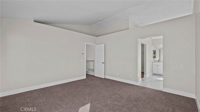 unfurnished bedroom featuring lofted ceiling, carpet, baseboards, and connected bathroom