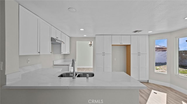 kitchen featuring white cabinetry, light stone countertops, sink, and a wealth of natural light