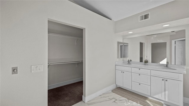 full bath with marble finish floor, a sink, baseboards, and double vanity