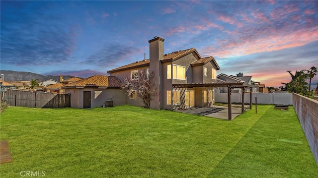 back house at dusk featuring a yard, a pergola, and a patio