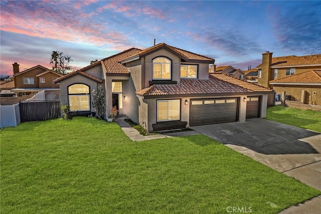 mediterranean / spanish home with an attached garage, fence, driveway, stucco siding, and a front yard