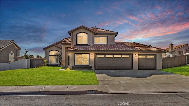 mediterranean / spanish-style home with a front lawn, an attached garage, fence, and a tile roof