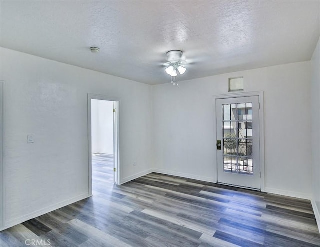 unfurnished room featuring a textured ceiling and dark hardwood / wood-style flooring