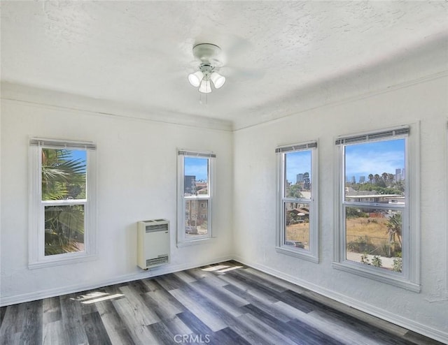 empty room featuring heating unit, ceiling fan, dark hardwood / wood-style floors, and a textured ceiling