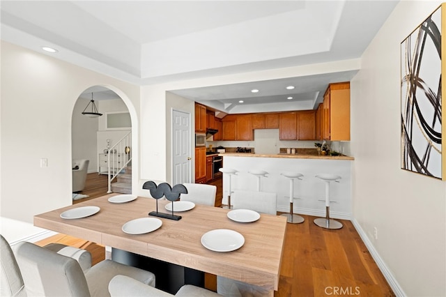 dining space with light hardwood / wood-style flooring and a raised ceiling