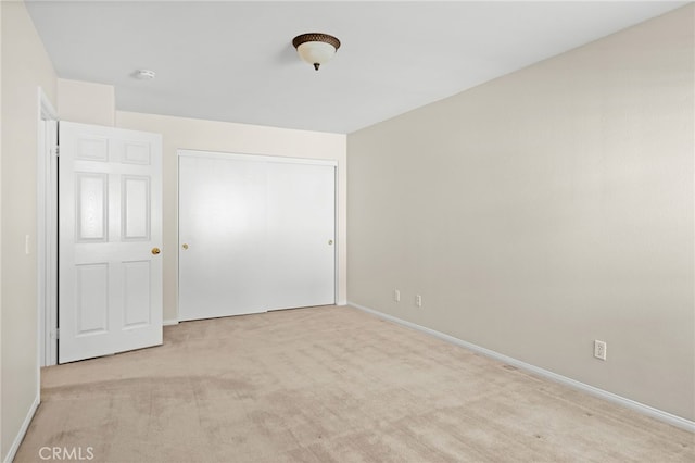 unfurnished bedroom with light carpet and a closet