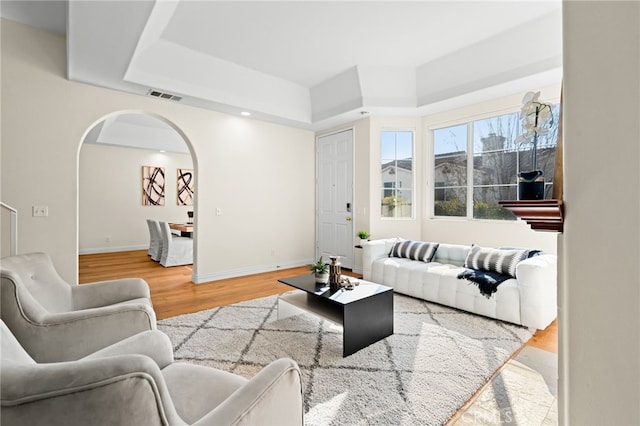 living room with hardwood / wood-style flooring and a raised ceiling